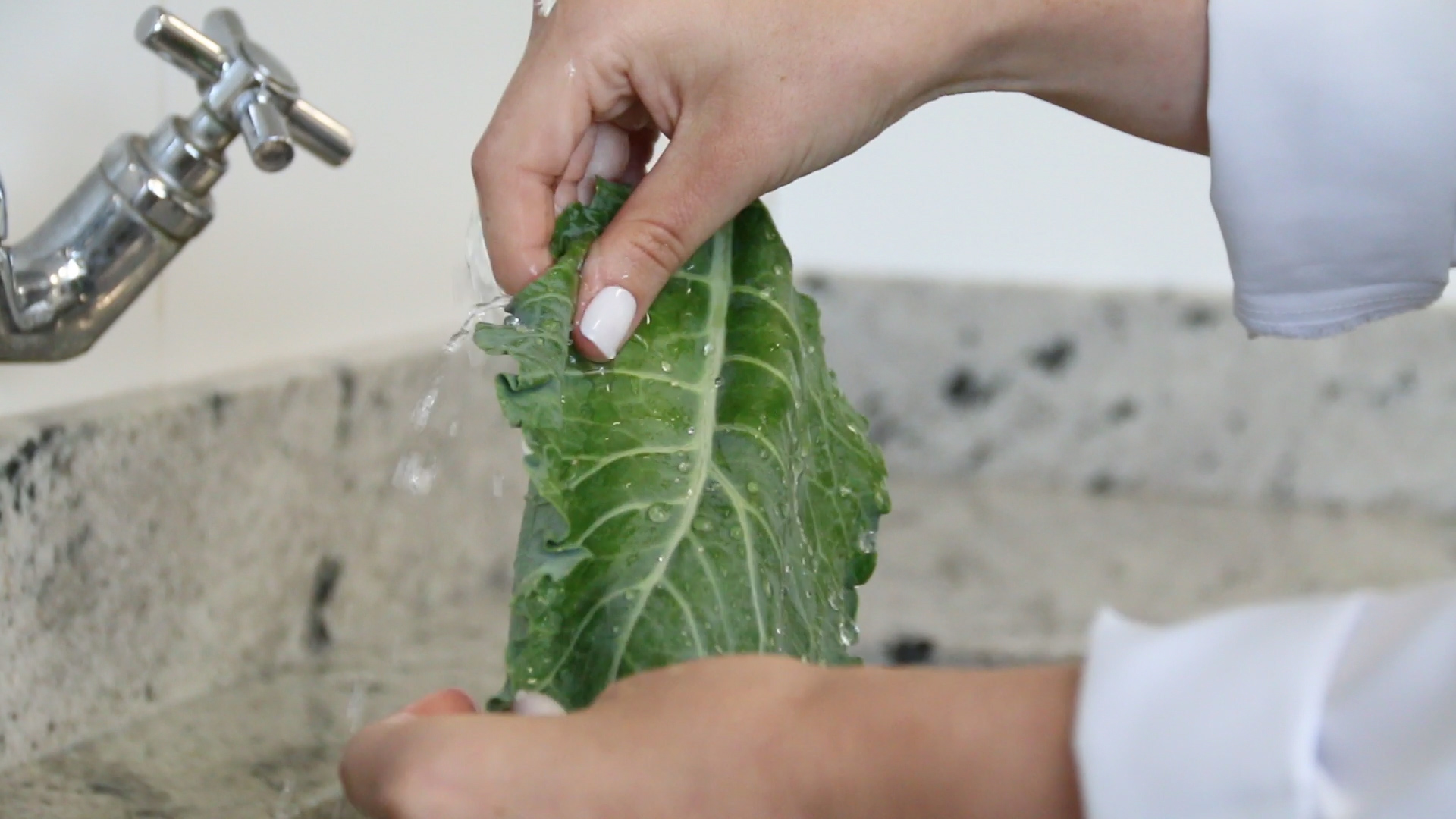 Imagem mostra nutricionista Ana Júlia Arend, do Espaço Viver Bem Unimed, lavando folhas verdes em água corrente