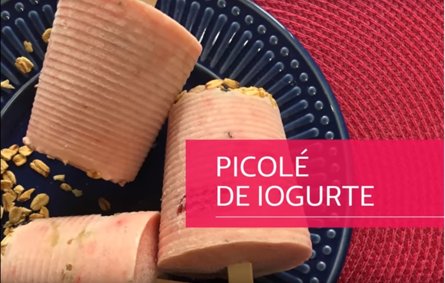 Imagem mostra três picolés de iougurte com grão de granola em um prato preto