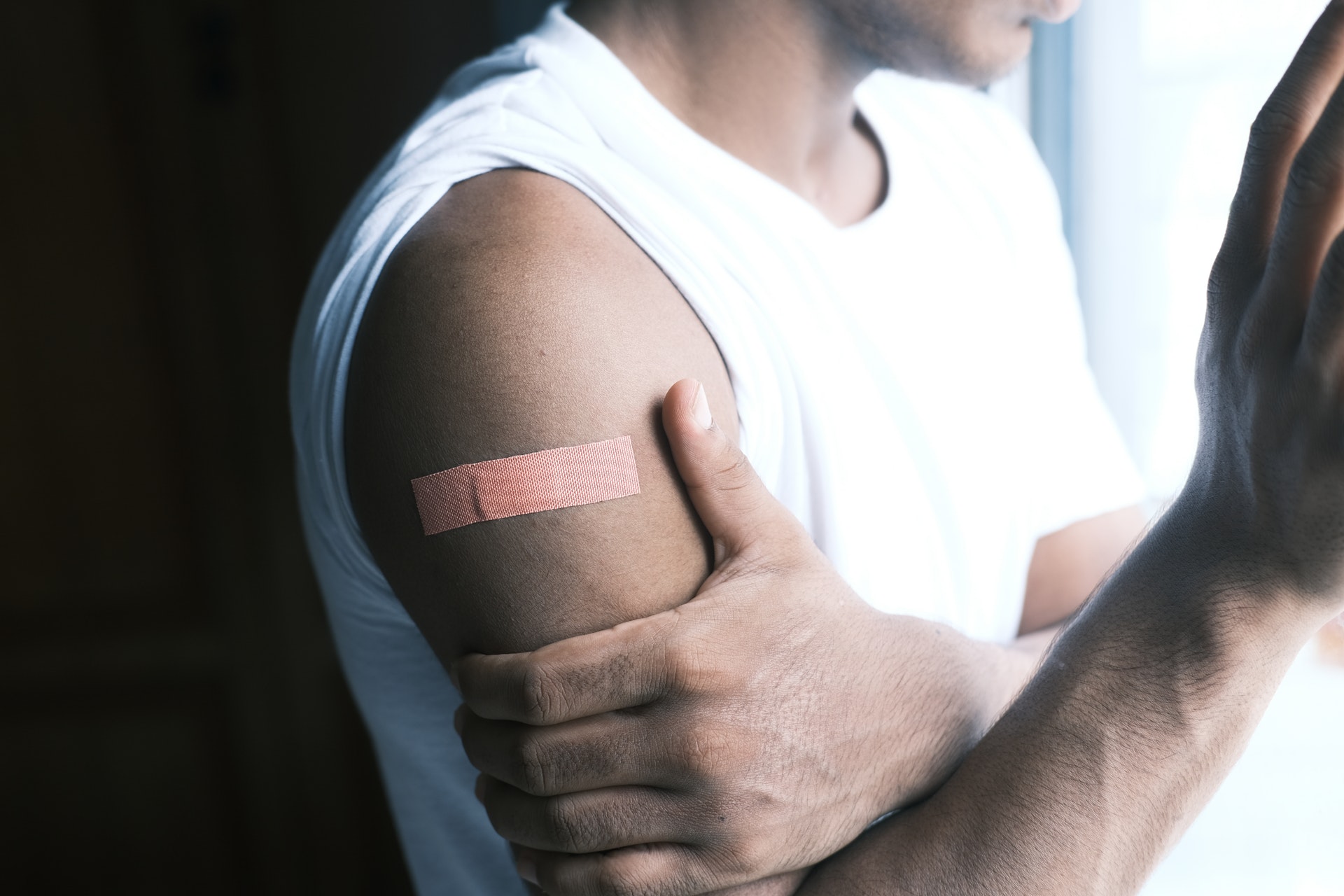 Imagem de um homem com curativo de vacina no braço